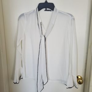 White blouse with black piping.